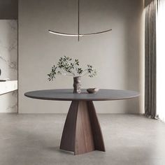 a round table with two vases on it in front of a white wall and window