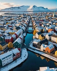 an aerial view of a city with snow on the ground and mountains in the background