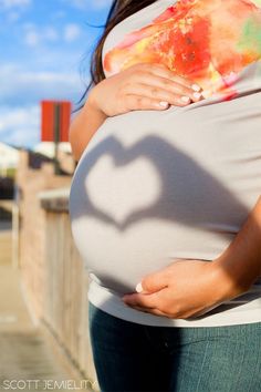 a pregnant woman holding her stomach with the shadow of a heart on it's belly