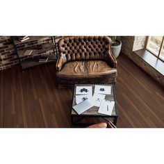 a brown leather chair sitting on top of a hard wood floor next to a table