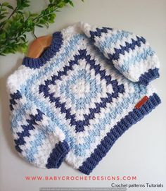 a blue and white sweater sitting on top of a wooden board next to a potted plant