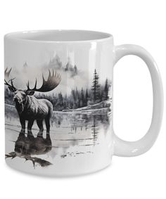 a coffee mug with an image of a moose in the water and mountains behind it