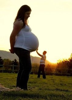 a pregnant woman holding the belly of a young man