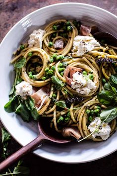 a white bowl filled with pasta, peas and fettuccine on top of a table