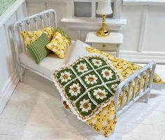 a crocheted bed with yellow and green pillows on it next to a lamp