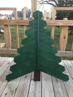 a green wooden christmas tree on a deck