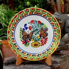 a colorful plate sitting on top of a wooden stand next to potted planters