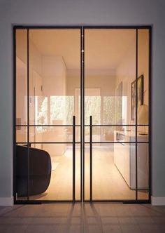 an open glass door leading into a living room with wood flooring and white walls