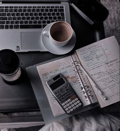 an open notebook, calculator and coffee on a desk