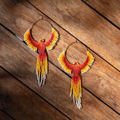 two pairs of hoop earrings with beaded fringes on wooden floor next to wood plank