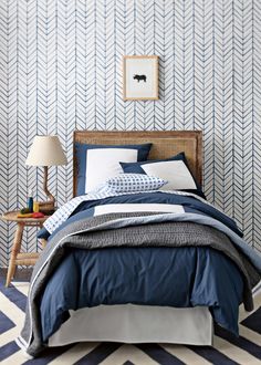 an image of a bedroom with blue and white decor on the walls, bedding and pillows