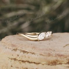 an engagement ring with three stones sitting on top of a rock