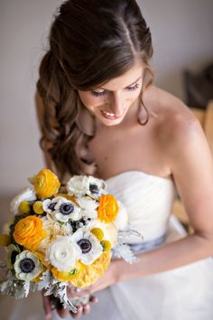 a bride holding a bouquet of yellow and white flowers