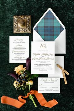 the wedding stationery is laid out on green velvet