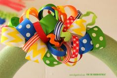 a close up of a colorful hair bow on a green wreath with polka dots and ribbons