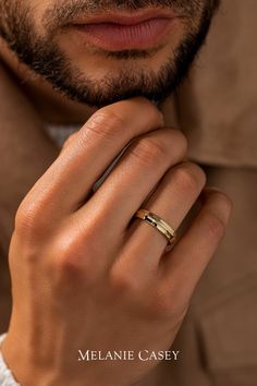 a close up of a person wearing a gold ring with a white shirt and brown jacket