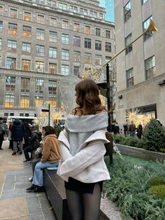 a woman in tights is standing on the street corner with her back to the camera