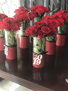 red roses in vases with numbers on them sitting on a table next to a mirror