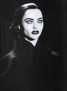 a black and white photo of a woman with dark makeup