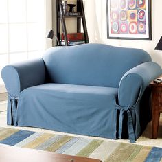 a blue couch in a living room next to a lamp and table with a painting on the wall