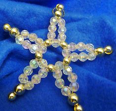 a cross made out of glass beads on a blue cloth with gold colored beading