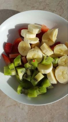 a white bowl filled with sliced fruit on top of a table