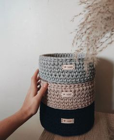 a person holding three baskets on top of a wooden table