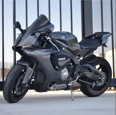 a black yamaha motorcycle parked in front of a fence