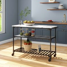 a kitchen with blue walls and wooden flooring has a white marble top table on wheels