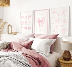 a bed with pink sheets and pillows in a bedroom next to two pictures on the wall