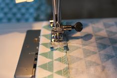 the sewing machine is on top of the quilted tablecloth with an open zipper