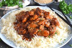 a white plate topped with rice and meat covered in gravy on top of a table