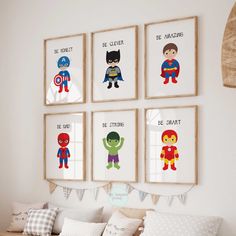 a bedroom with four framed superheros on the wall and one bed in front of it