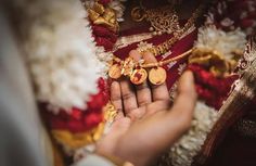 a close up of a person's hand holding some gold jewelry on her wedding day