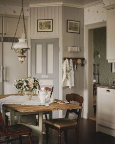 a kitchen table with two chairs and a vase filled with flowers on top of it