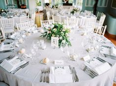 the table is set with white linens and silverware for an elegant wedding reception