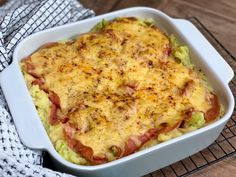 a casserole dish with meat and vegetables in it on a cooling rack next to a towel