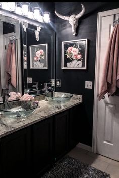 a bathroom with two sinks and a cow skull mounted on the wall above it's mirror