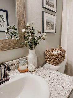 a bathroom with a sink, toilet and flowers in a vase on the counter top