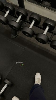 the person is standing in front of some dumbbells with their feet on them