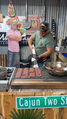 a man cooking food on top of a grill next to a sign that says cajun two streets