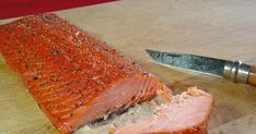 a piece of salmon sitting on top of a cutting board next to a knife