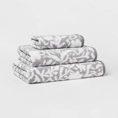 three towels stacked on top of each other in front of a white background with an ornate pattern