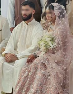 two people sitting next to each other in front of a man and woman wearing wedding attire