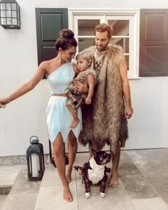 a man, woman and child are dressed up as cave dwellers with a dog in front of a house