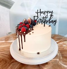 a birthday cake with berries and chocolate drips