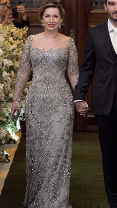 a man and woman in formal wear walking down the aisle