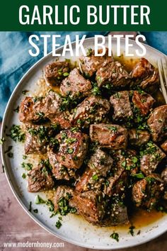 garlic butter steak bites on a white plate with a fork and parsley garnish