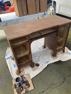 a wooden desk sitting on top of a tarp covered ground next to a van