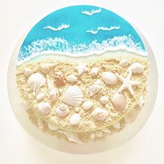 there is a cake decorated with seashells on the beach